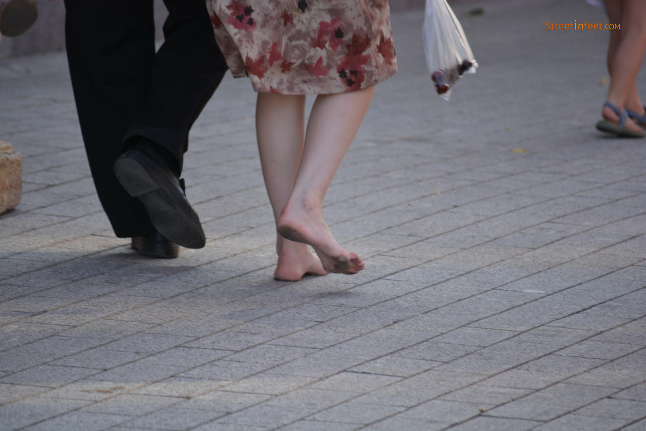 Barefoot girl walking in street whith dirty feet by 
